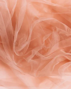 Textura de tule rosa-salmão usado em vestido infantil de festa